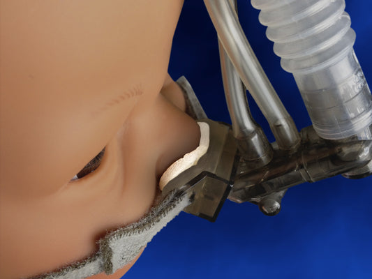 NeoSeal de Neotech sobre las puntas de una cánula nasal en un maniquí neonatal, lado suave hacia la piel