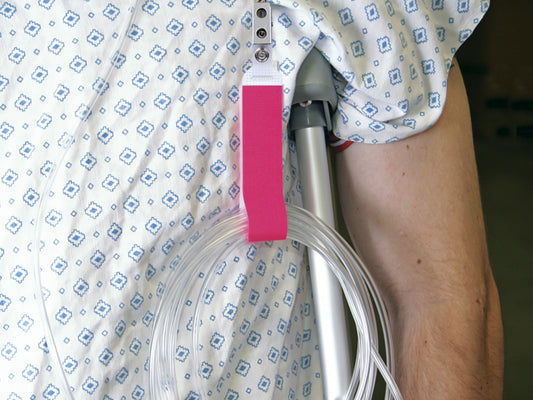 NeoGrip N602P de Neotech, color rosa, sujetando tubos a la bata de un paciente