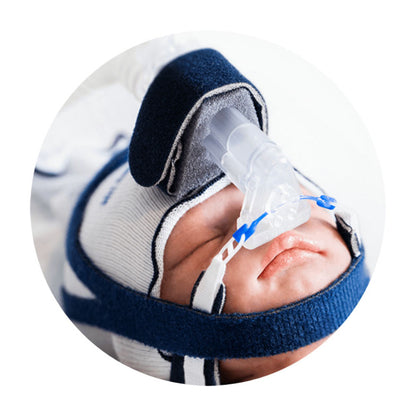 Recién nacido con interfaz FlexiTrunk Fisher & Paykel, mascarilla nasal y gorro, foto oficial